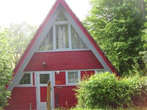 a red house with a gambrel roof at Wooden bungalow with a terrace in a wooded area in Berneburg