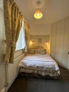 a bedroom with a bed and a window at Historic 2 bed gatehouse in private parkland in Brockenhurst