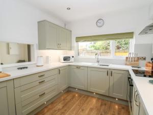 a kitchen with white cabinets and a sink and a window at Ty Melyn in Aberystwyth