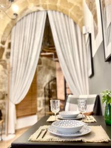 a table with two plates and wine glasses on it at 300yr old, self catering, tiny house in Victoria Centre, Gozo in Victoria