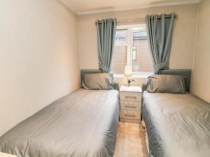 two beds in a small room with a window at Woodpecker Lodge in Beaworthy