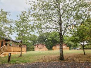 a couple of cottages in a park with a tree at Woodpecker Lodge in Beaworthy