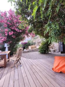 eine Holzterrasse mit einem Stuhl, einem Tisch und Blumen in der Unterkunft The Cosy Home Corbara by 1722 in Corbara