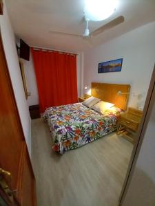 1 dormitorio con cama y cortina roja en alojamientosmomi3, en Corralejo