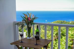 a table with two glasses of wine and a vase of flowers at Morne SeaView Apartments in Castries