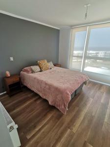 1 dormitorio con cama grande y ventana grande en Departamento Vacacional Algarrobo-Yeco, en Yeco