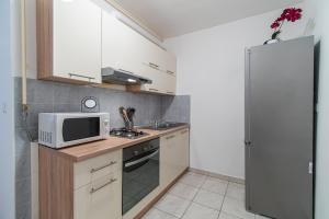 a small kitchen with a microwave and a refrigerator at Flexible SelfCheckIns 34 - Zagreb - Parking - Big Loggia - New in Zagreb