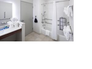 uma casa de banho branca com um chuveiro e um lavatório. em Holiday Inn Express & Suites - Orlando At Seaworld, an IHG Hotel em Orlando