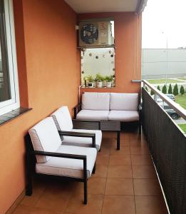 d'un balcon avec des chaises blanches et une horloge murale. dans l'établissement Apartament na Brudzewskiego, à Przemyśl