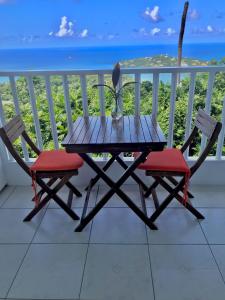 einen Holztisch und zwei Stühle auf einem Balkon mit Meerblick in der Unterkunft Morne SeaView Apartments in Castries