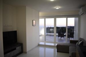 a living room with a couch and a large glass window at Sunset and Seaview Apartment -Brand New in Mellieħa