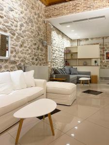 a living room with white furniture and a stone wall at Blue Domino Luxury City Villa Patras in Patra