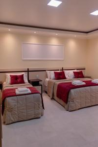 サン・ビセンテにあるHAUER HOTELの赤い枕付きのベッド2台が備わる客室です。