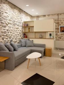 a living room with a gray couch and a stone wall at Blue Domino Luxury City Villa Patras in Patra