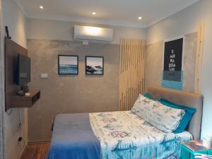 a small bedroom with a bed and a tv at Estúdio Praia residence in Santos
