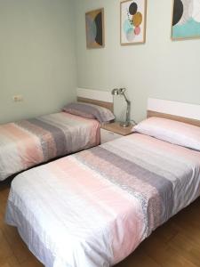 two beds in a room with white and pink sheets at Apartamento Las Huellas in Arnedillo