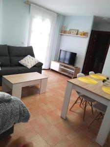uma sala de estar com um sofá, uma mesa e uma televisão em Apartamento Las Huellas em Arnedillo