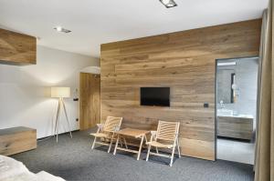 a bedroom with a wooden wall with a table and chairs at Guest House Hiša Denk in Zgornja Kungota