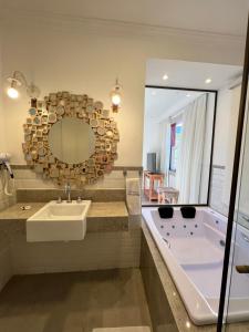 een badkamer met een bad, een wastafel en een spiegel bij Pousada Tiradentes in Tiradentes