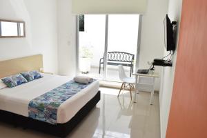 a bedroom with a bed and a desk and a window at Color House Santa Marta in Santa Marta