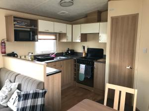 a small kitchen with a couch and a stove at 3 Bed Caravan Lido Beach in Prestatyn