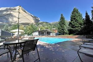 a table with an umbrella next to a swimming pool at JHRL - Slope-side Four Seasons 1 #1 Condo - Walk to Tram in Teton Village