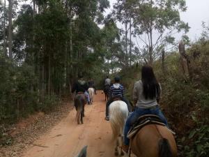 um grupo de pessoas andando a cavalo por uma estrada de terra em Suite com terraço em Conceição da Ibitipoca