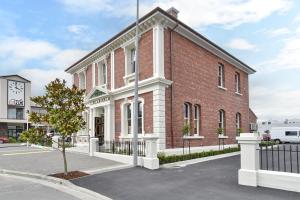 a red brick building with a black fence in front of it at Kaiapoi Luxury Accommodation 1 - Bookahome in Kaiapoi