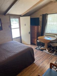 a bedroom with a bed and a desk and a table at Woodland Motor Lodge in Grayling