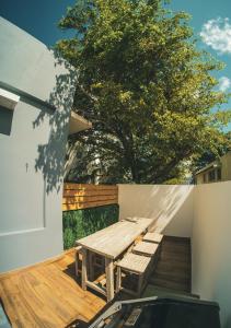 een houten tafel en banken op een terras met een boom bij SOKZO Miramar in San Juan