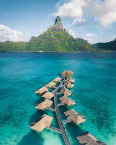 an island with straw islands in the water at InterContinental Bora Bora & Thalasso Spa, an IHG Hotel in Bora Bora
