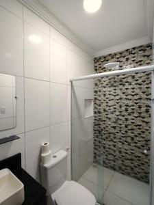 a bathroom with a toilet and a glass shower at Pousada do Alemão in Maragogi