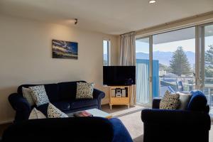 a living room with a blue couch and a tv at Waves on the Esplanade in Kaikoura