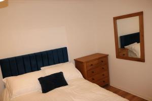 Entire -4 Bedrooms Detached House with Driveway في نوتينغهام: غرفة نوم مع سرير مع مرآة وخزانة