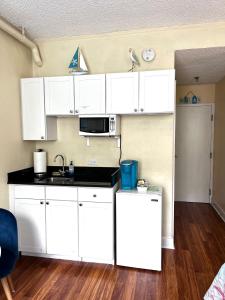 a kitchen with white cabinets and a white refrigerator at Cozy Studio in the Heart of the Palm Beach Island in Palm Beach