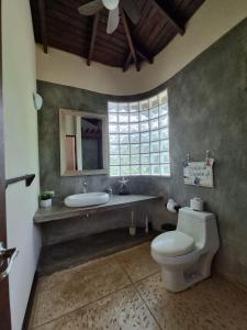 a bathroom with a toilet and a sink and a window at Beach Walk Costa Rica in Playa Avellana
