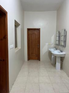 a bathroom with a sink and a wooden door at Albashier private apartment in AlUla