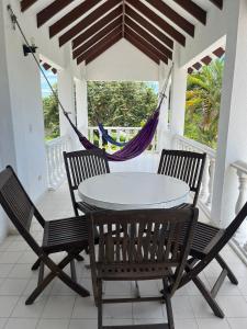 a table and chairs on a porch with a hammock at CASA ABEDULES 14 CONDOMINIO RESIDENCIAL SAN MARCOS POBLADO in Ricaurte