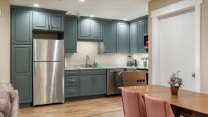 eine Küche mit grünen Schränken, einem Tisch und einem Kühlschrank in der Unterkunft Teton Crest Apartment in Driggs