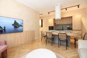 a dining room and kitchen with a tv on a wall at Beige Apartment in Sarajevo