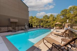 a swimming pool with chairs and a building at Best Western Plus Russellville Hotel & Suites in Russellville