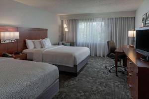 a hotel room with two beds and a desk and a television at Sonesta Select Chattanooga Hamilton Place in Chattanooga