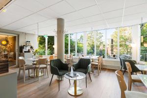 ein Restaurant mit Tischen und Stühlen und großen Fenstern in der Unterkunft Best Western Hotel Danderyd in Danderyd