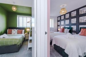 twee bedden in een kamer met groen en roze bij R&R - Modern Townhouse near Etihad & City Centre (5 Bedrooms, Free Parking) in Manchester