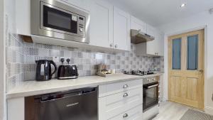 a kitchen with white cabinets and a microwave at Princely House Corporate, business & family Home in Mansfield
