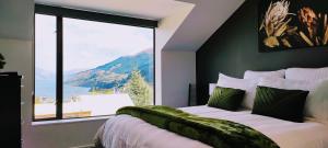 a bedroom with a bed and a large window at Stunning Home with Amazing Wakatipu Lake Views in Queenstown