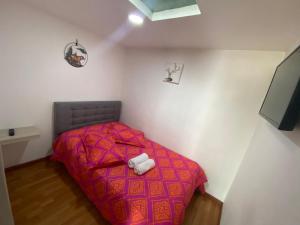 Dormitorio pequeño con cama con edredón rojo en Viveros 2 hab moderno, tranquilo y familiar., en Manizales