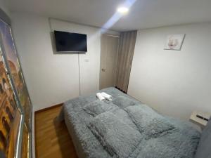 マニサレスにあるViveros 2 hab moderno, tranquilo y familiar.のベッドと壁にテレビが掛かった寝室