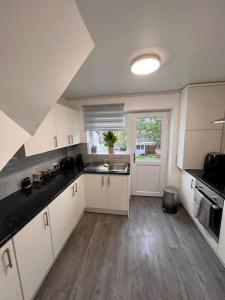 a large kitchen with white cabinets and a large window at Cosy home in Rochester, sleeps 6 in Strood