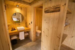 Baño de madera con lavabo y espejo en Hermoso Eco Lodge en San Martín de los Andes